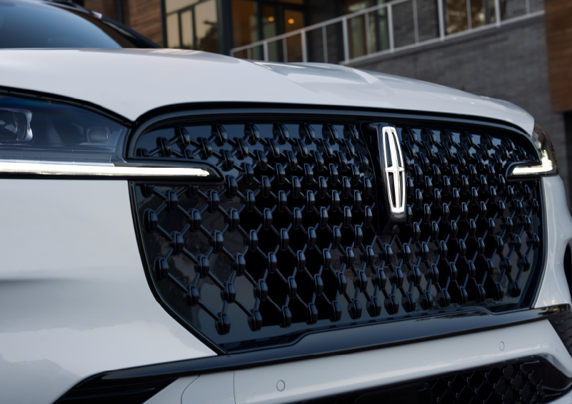 The black grille of a white 2025 Lincoln Aviator® SUV is shown with its fog lights on. | Gates Lincoln in Richmond KY