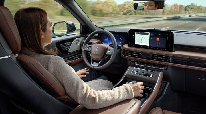 A 2026 Lincoln Aviator® SUV is being driven hands-free on a highway near a forest | Gates Lincoln in Richmond KY